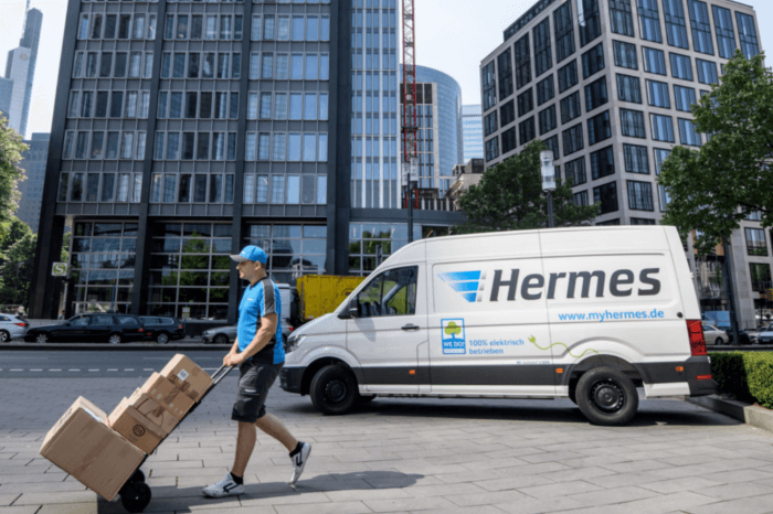 Ein junger Mann liefert mit seinem HERMES-Transporter aus