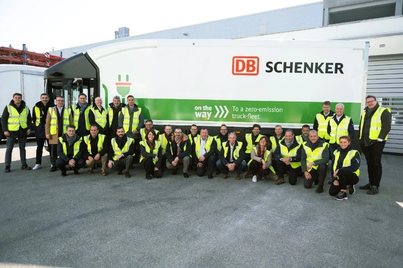 Mehrere Arbeiter posieren für ein Foto mit einem DB Schenker-Lkw im Hintergrund.