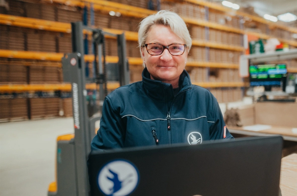 Eine Frau in einem Lager mit ihrem Computer.